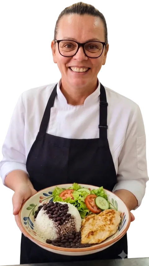 Chef Ana Cristina sorrindo, segurando um prato com frango grelhado, arroz, feijão e salada